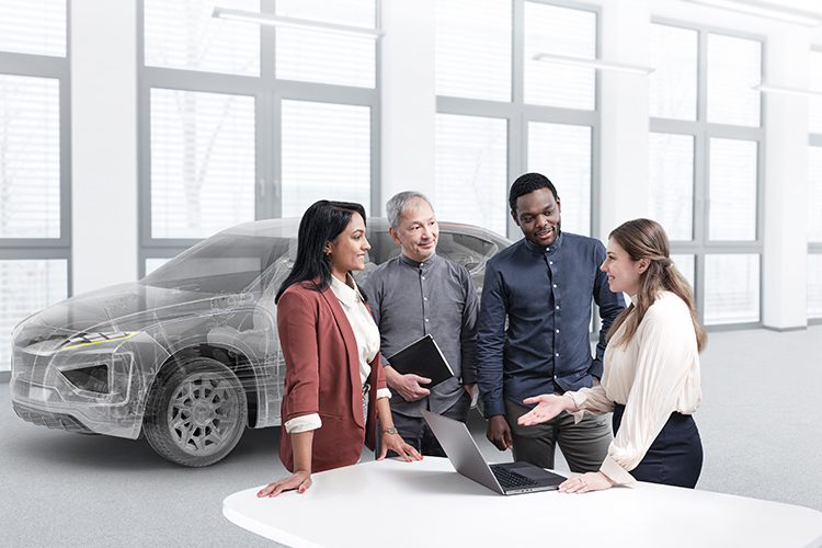 People standing at a table looking at a laptop with a ghosted vehicle in the background