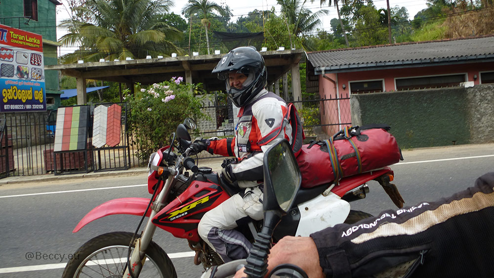 Rebecca Kleis on motorcycle driving through a small town