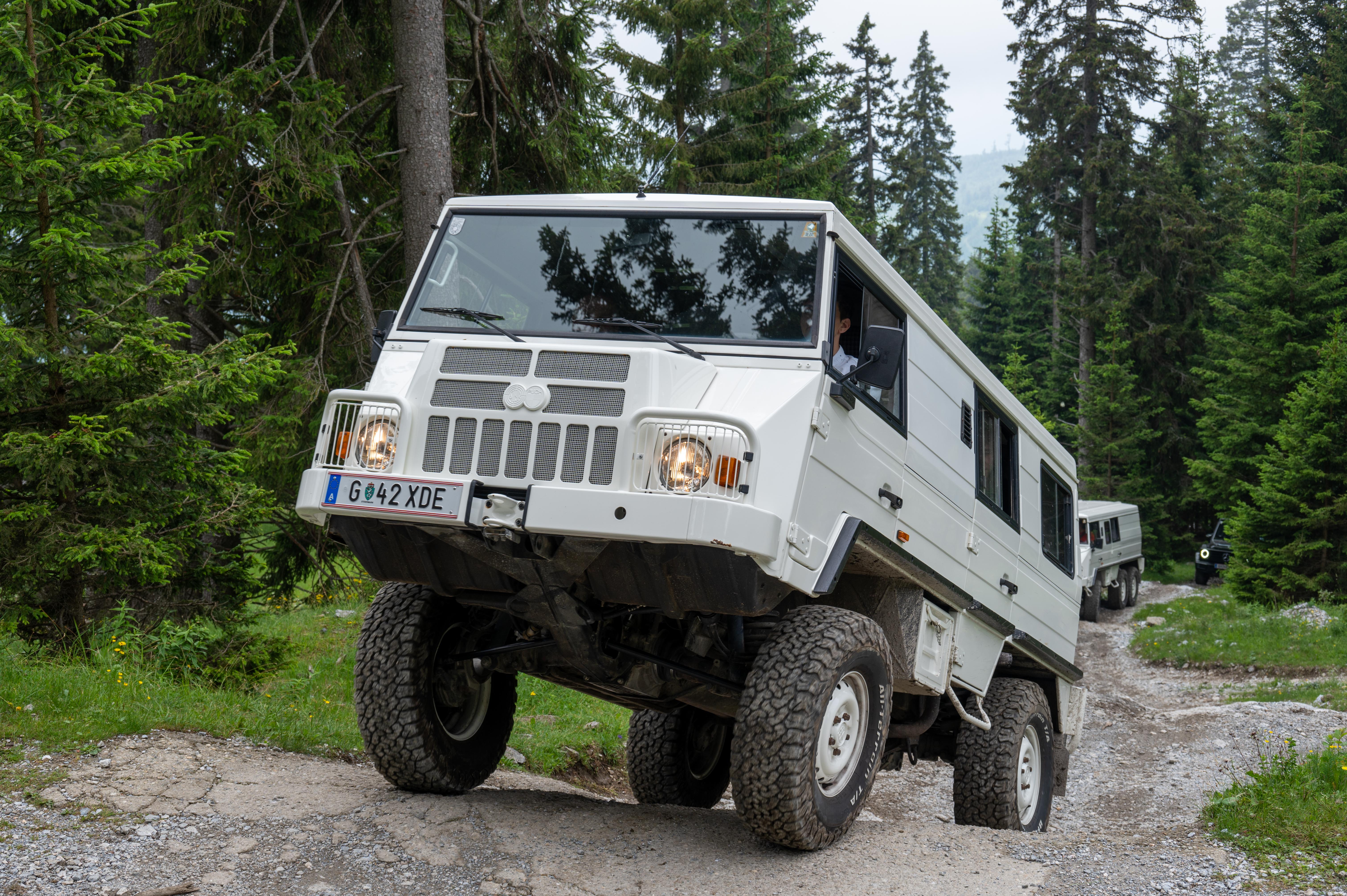 Large off-road vehicle driving on a rocky forest trail