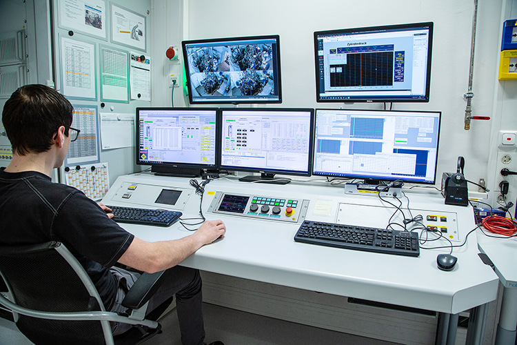 Person sitting in front of monitors for the High Altitude & Climate Test Bench in a manufacturing facility