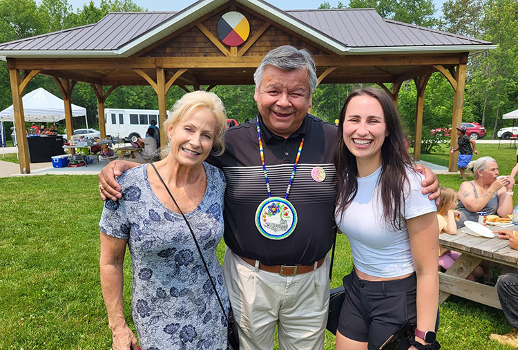 Three people with their arms around each other at a picnic