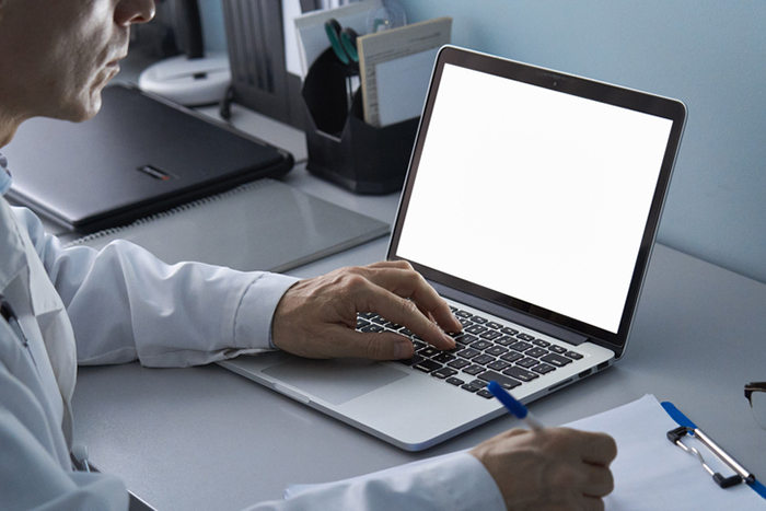 Person in a lab coat using a laptop with a blank screen