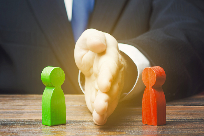 Hand separating green and red wooden figures on a table